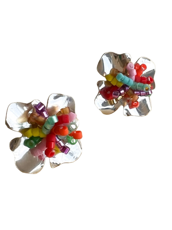 Silver flower-shaped earrings with colorful beads on a beige background