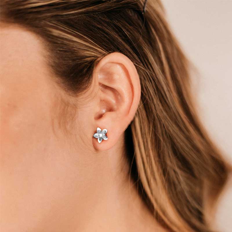 Close-up of a person wearing a silver flower-shaped earring.