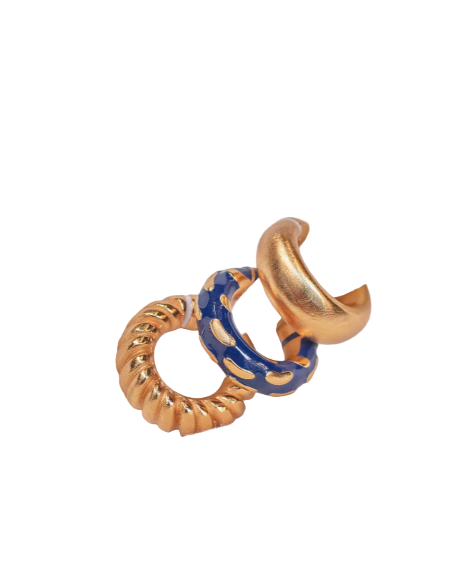 A set of three earcuffs in gold and blue colors placed on a white surface.
