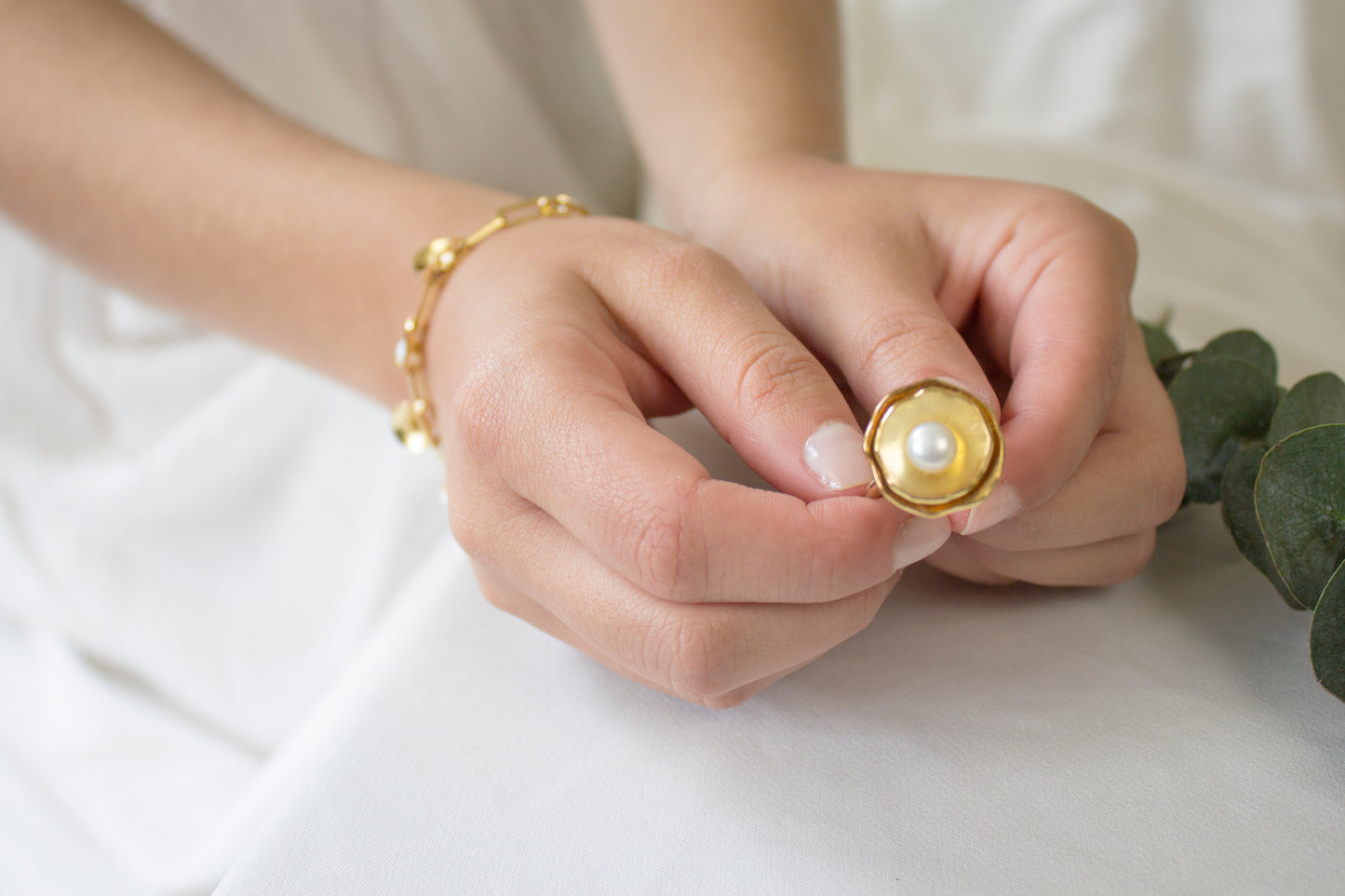 A person's hand holding a bronze ring with 24k gold plating and an adjustable fit.