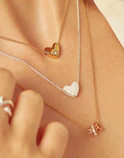 Close-up of necklaces with heart-shaped pendants on a person's neck.