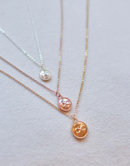 Three necklaces with different colored pendants on a light gray background