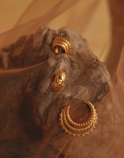 Gold hoop earrings on a textured brown fabric background