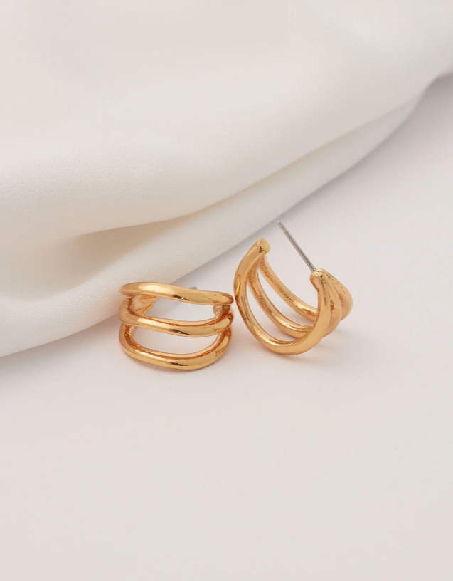 Gold hoop earrings on a white fabric background
