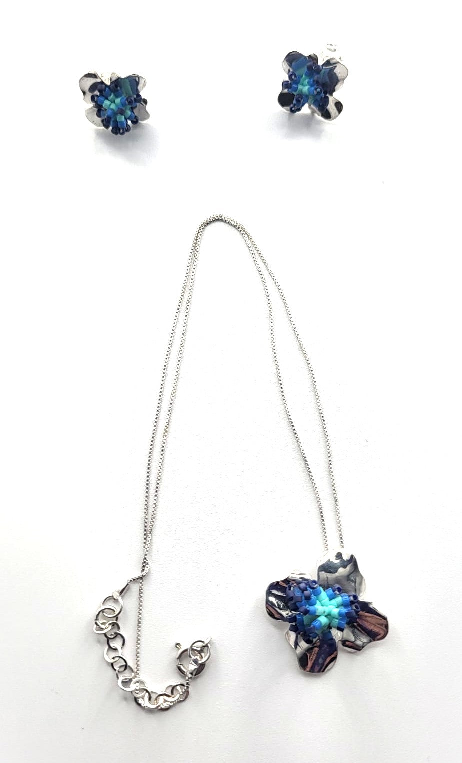 Jewelry set with necklace and earrings featuring blue gemstones on a white background