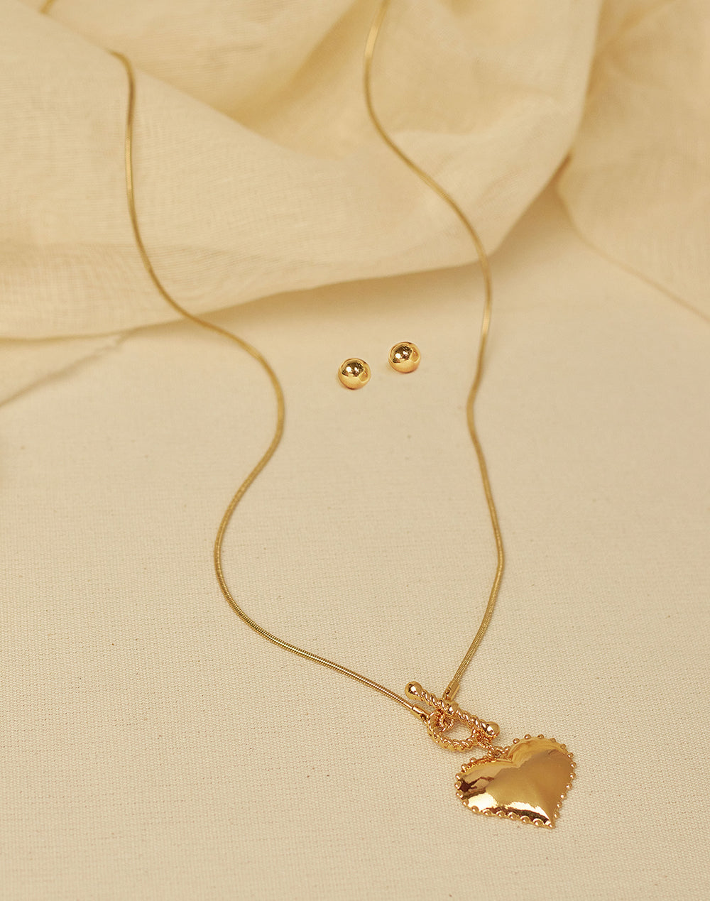 Gold necklace and earrings on beige fabric
