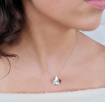 Silver necklace with a orchid flower pendant worn by a person