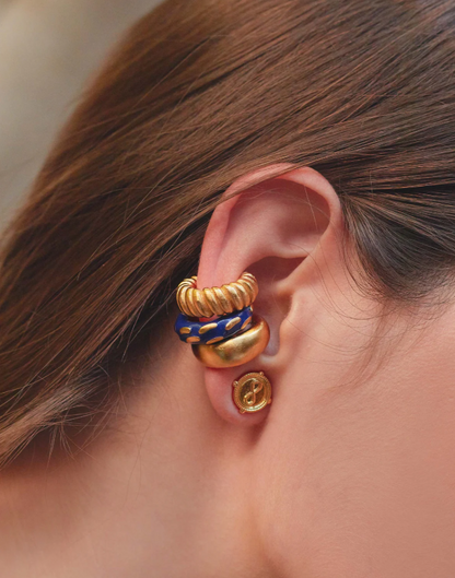 Close-up of a person's ear wearing a gold and blue earring.