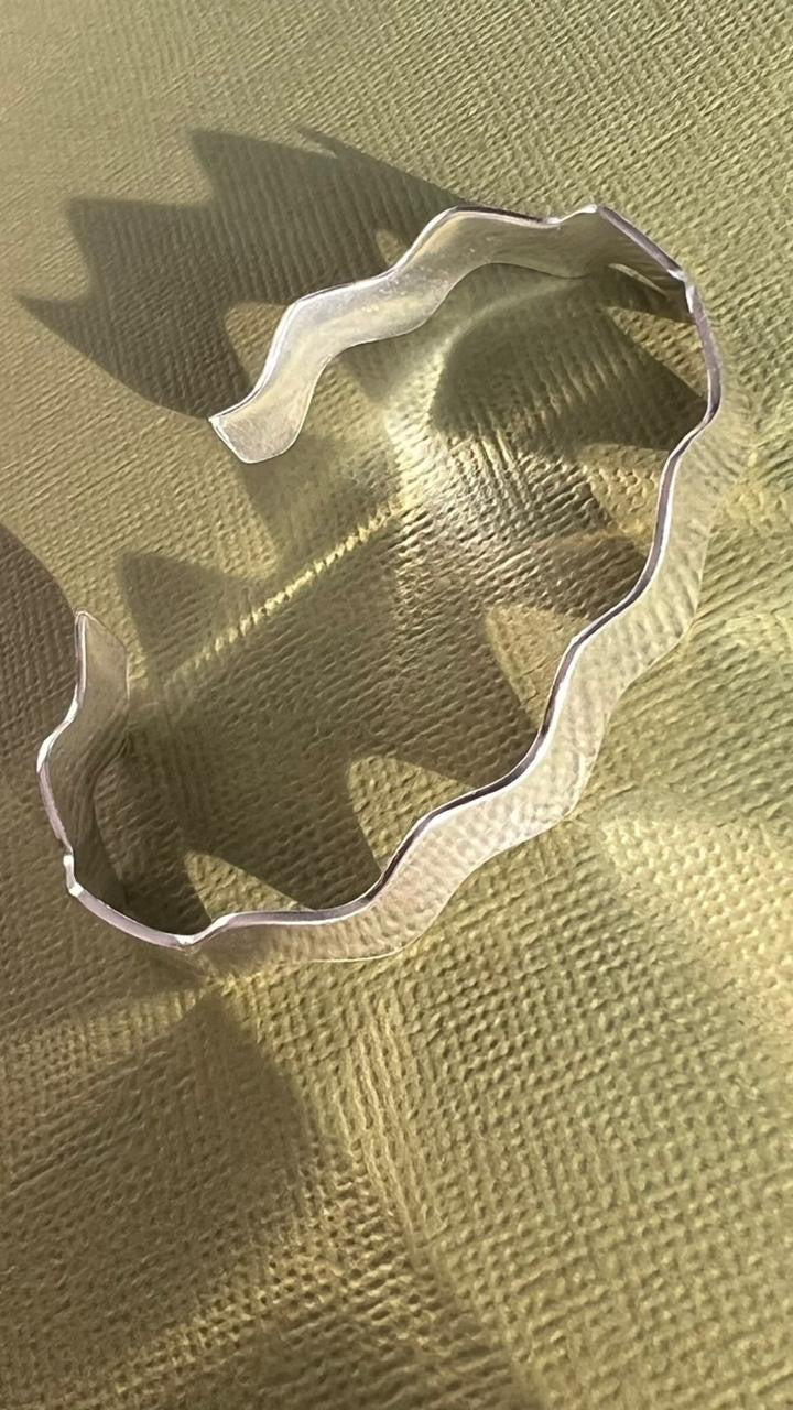 Ondas Silver Bracelet on a textured green surface