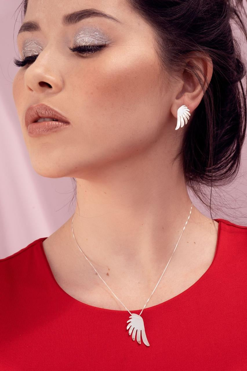 Woman wearing a silver necklace and earrings against a pink background
