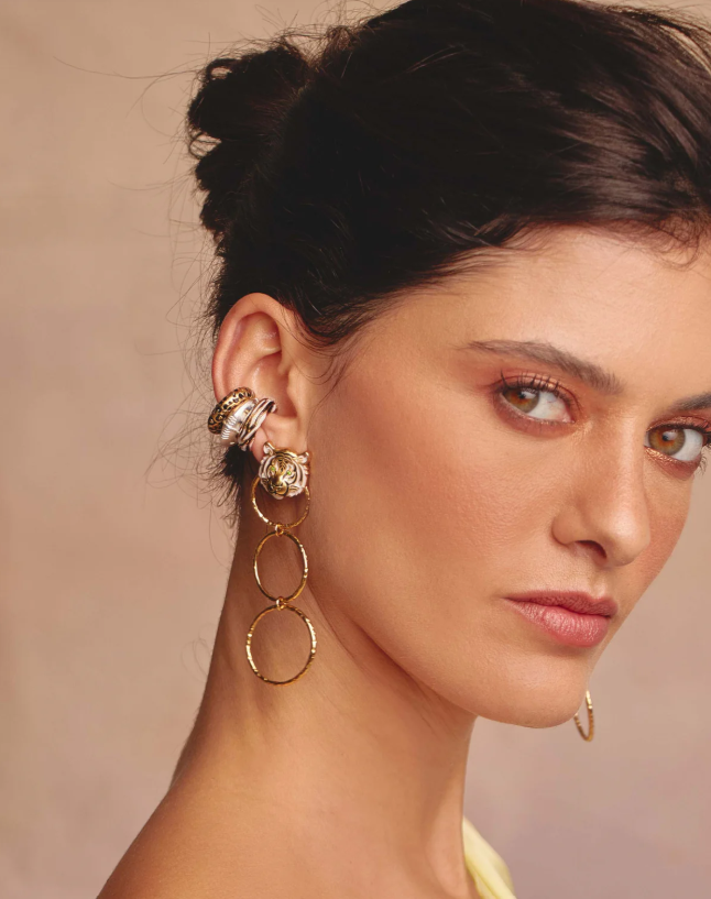 Woman wearing gold hoop earrings with a neutral background