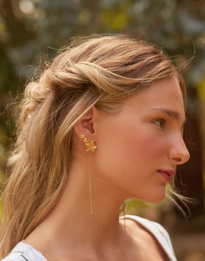 A person wearing a white dress and one of the earrings from the Lazos- Set of 5 Earrings – Secret Garden collection.