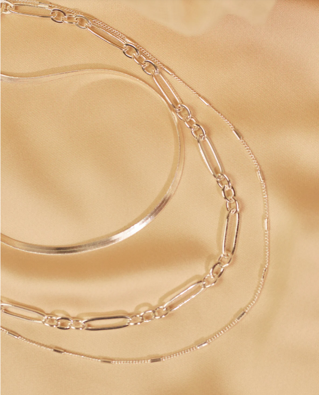 Silver chain necklace on a gold surface