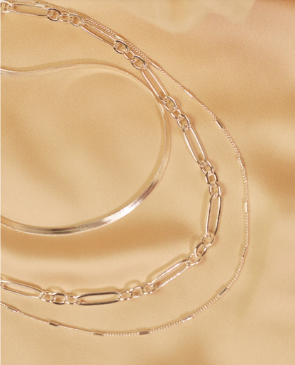 Silver chain necklace on a gold surface