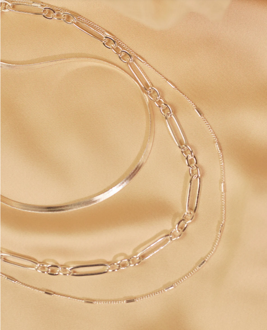 Silver chain necklace on a gold surface