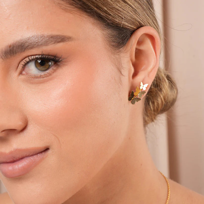 Close-up of a woman wearing Triple Butterfly Golden Earrings with a neutral background