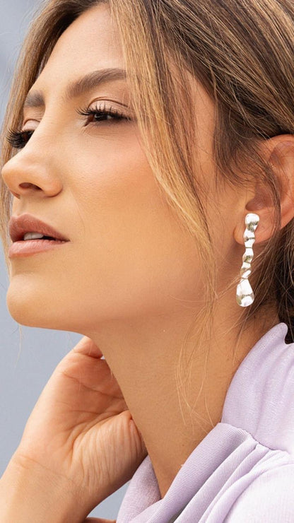 Close-up of a woman wearing rectangle-shaped earrings with a soft background