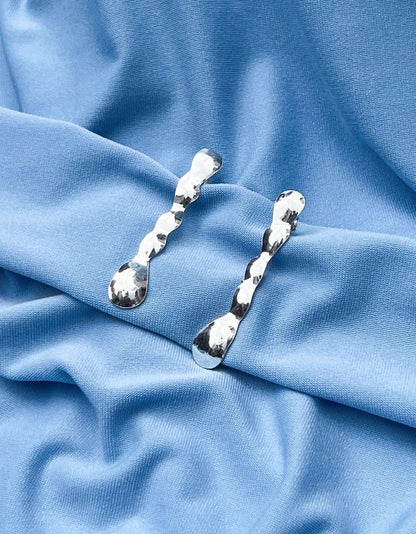 Silver earrings on a blue fabric background