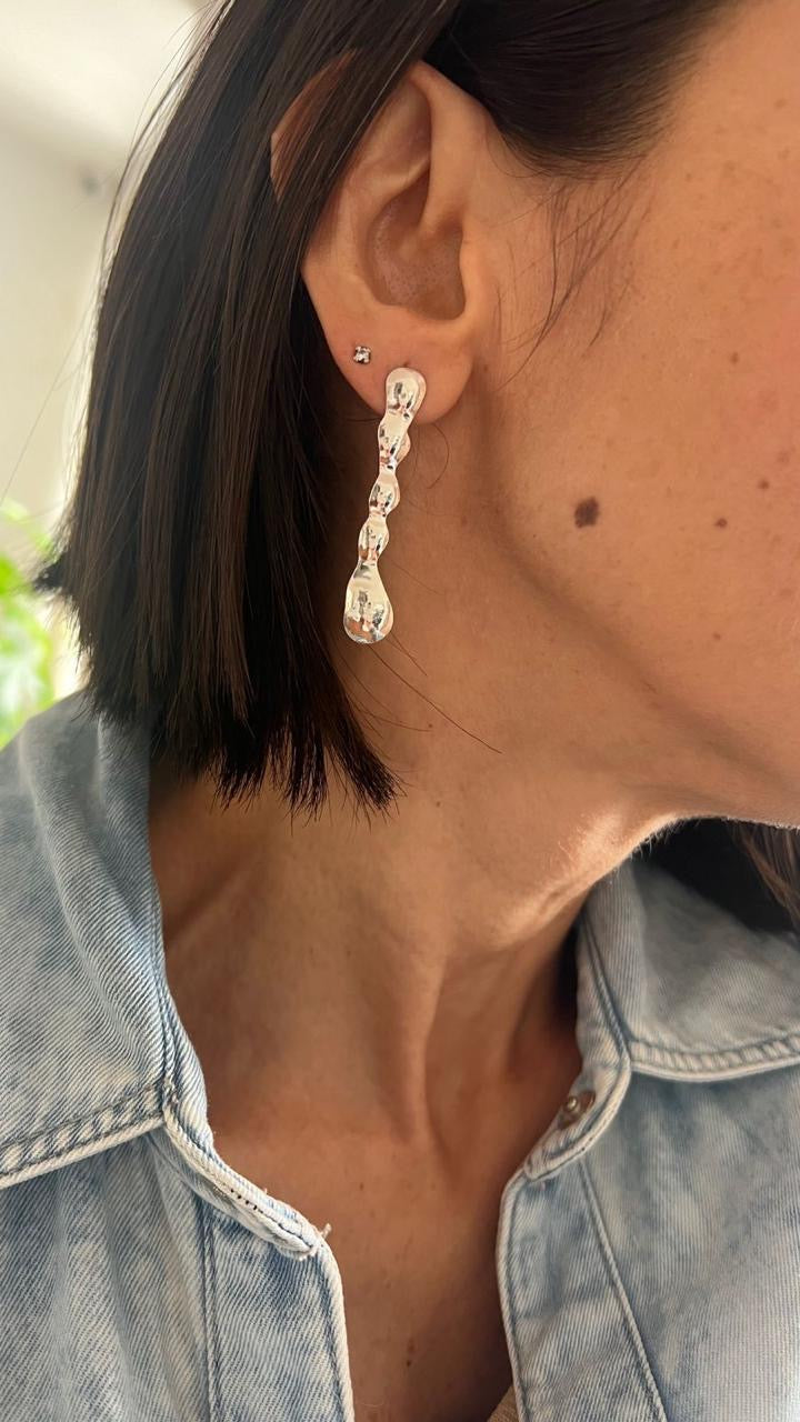Close-up of a person wearing a silver earring with a blurred background